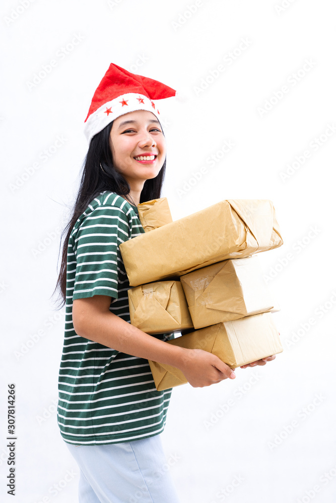 portrait of a young Asian woman wearing a santa hat and wearing casual clothes lifting a pile of gifts portrait of a young Asian woman wearing a santa hat and wearing casual clothes lifting a pile of gifts