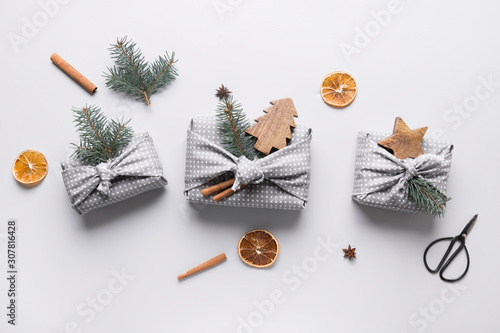 Christmas gifts wrapped in grey textile with natural decor. Sustainable gifts. Zero waste. Xmas eco holiday. Traditional Japanese Furoshiki style. View from above. Flat lay. photo