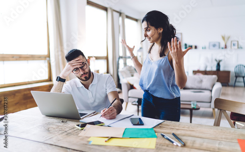 Indignant woman yelling at concentrated working boyfriend