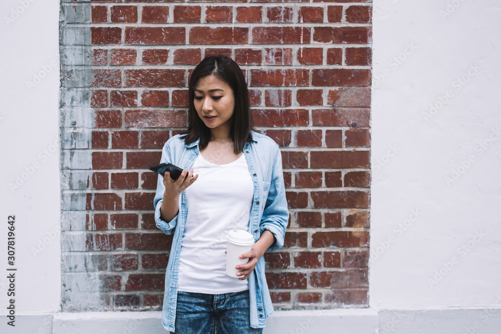 Asian woman using smartphone and drinking coffee on street