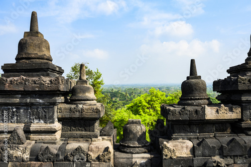 (Selective focus) Stunning view of a tropical forest in the background and blurred ruins of the Borobudur Temple in the foreground. Borobudur is a Mahayana Buddhist temple in Indonesia.