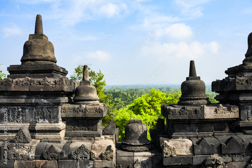 (Selective focus) Stunning view of the Borobudur temple ruins in the foreground and a blurred tropical forest in the background. Borobudur is a Mahayana Buddhist temple in Indonesia.