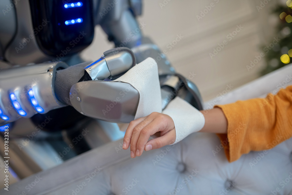 Robot carefully attaching bandage on girls wrist Robot carefully attaching bandage on girls wrist