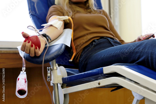 Blood donation, girl donor in chair with a red bouncy heart in hand. Concept of donorship, transfusion, health care photo