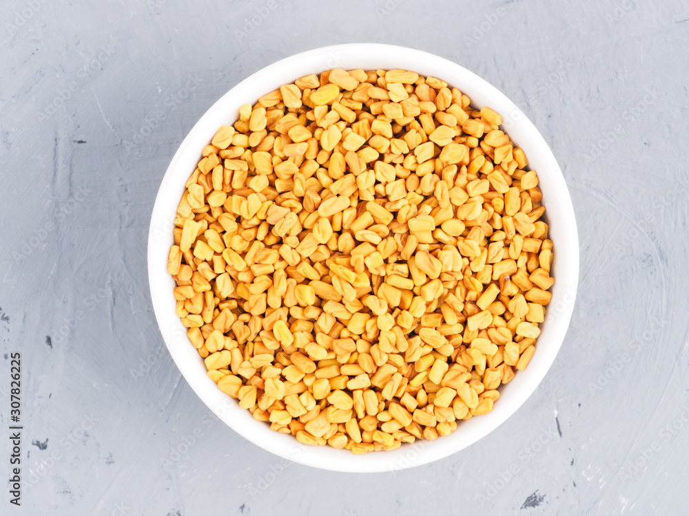 Fenugreek in a white bowl on a gray concrete background. Healthy eating concept Fenugreek in a white bowl on a gray concrete background. Healthy eating concept