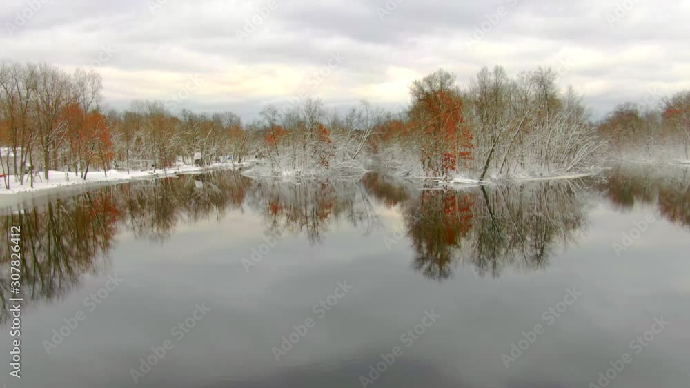 Snow coated trees beside the Peshtigo River reflected in dark November waters. Snow coated trees beside the Peshtigo River reflected in dark November waters.