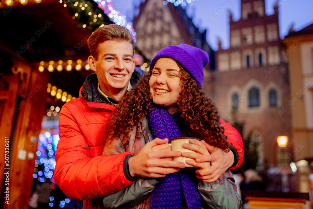 Young couple with drinks on Christmas market in Wroclaw, Poland