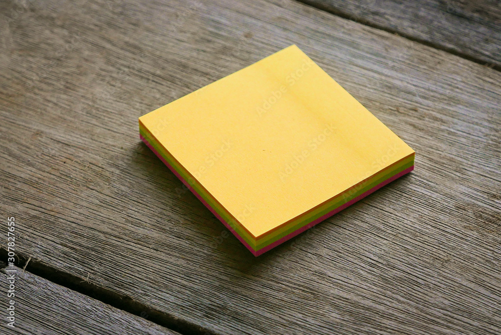 An empty yellow sticky notes on wooden background. An empty yellow sticky notes on wooden background.