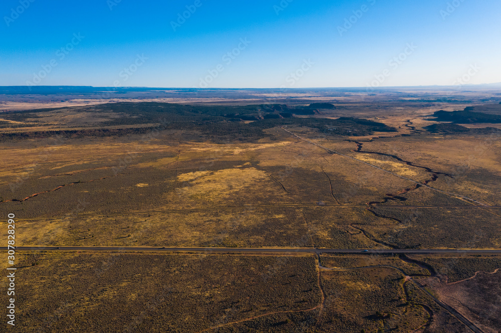 Aerial top view of highway road, fissure, cleft in the ground. Clear blue sky, evening. Arizona, USA