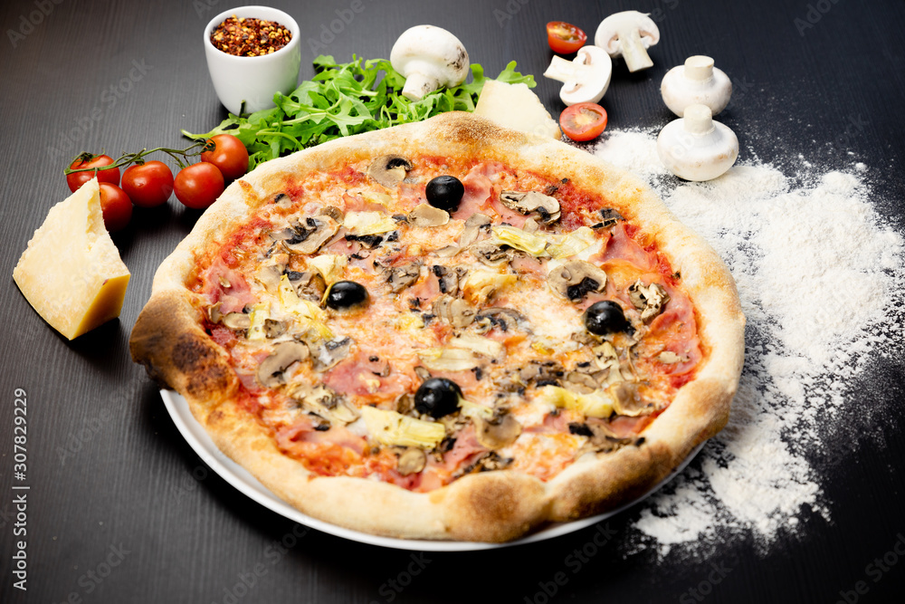 Declicious pizza with ingredients on the side, backed in traditional wooden oven.