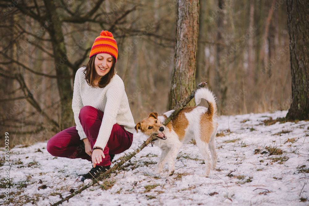 Young woman playing with her fox terrier in the forest. Best friend concept.