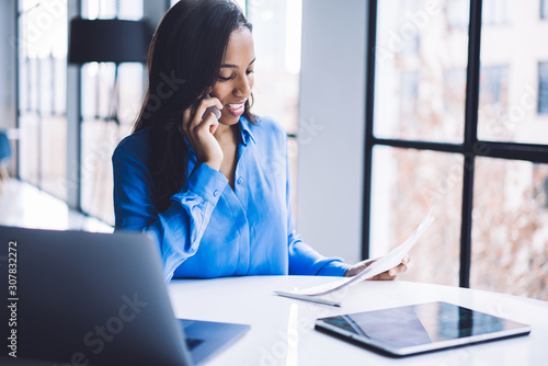 Photos Attentive black businesswoman talking on phone and revising document at work