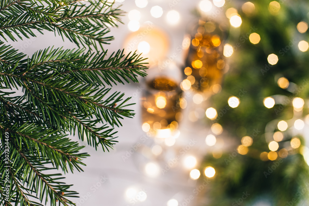 Obraz premium Christmas and New year background with tree branches, champagne glasses and glowing bokeh garland. Selective focus.
