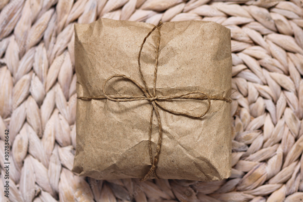 Parcel wrapping in brown craft paper and tie hemp string. Package. Delivery service. Online shopping. Your purchase. Gift box on a table. Decorative wood background. 