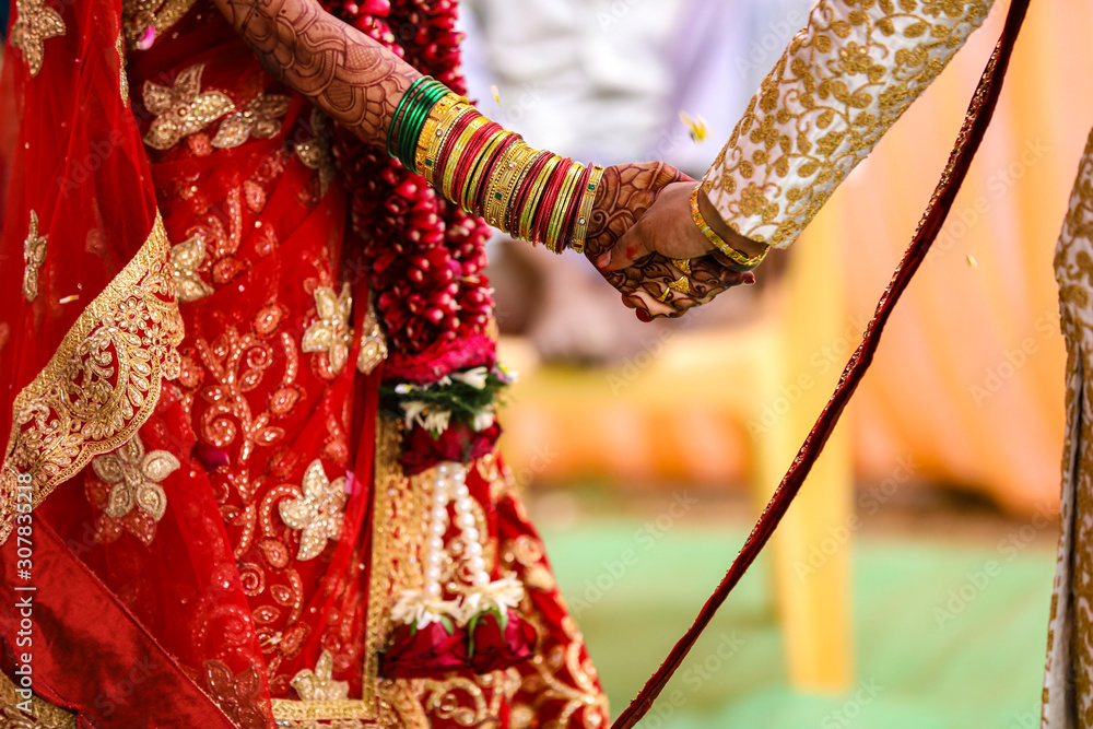 Traditional indian wedding ceremony, groom holding hand in bride hand