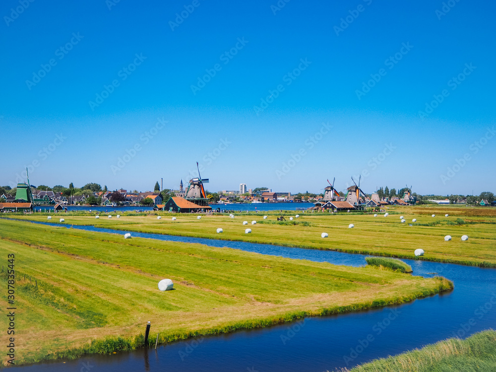 Naklejka premium Landscape with typical dutch windmill village Zaanse Schans in Zaandam, Netherlands. Traditional dutch windmills located by the river Zaan. Culture museum travel and scenery landscape