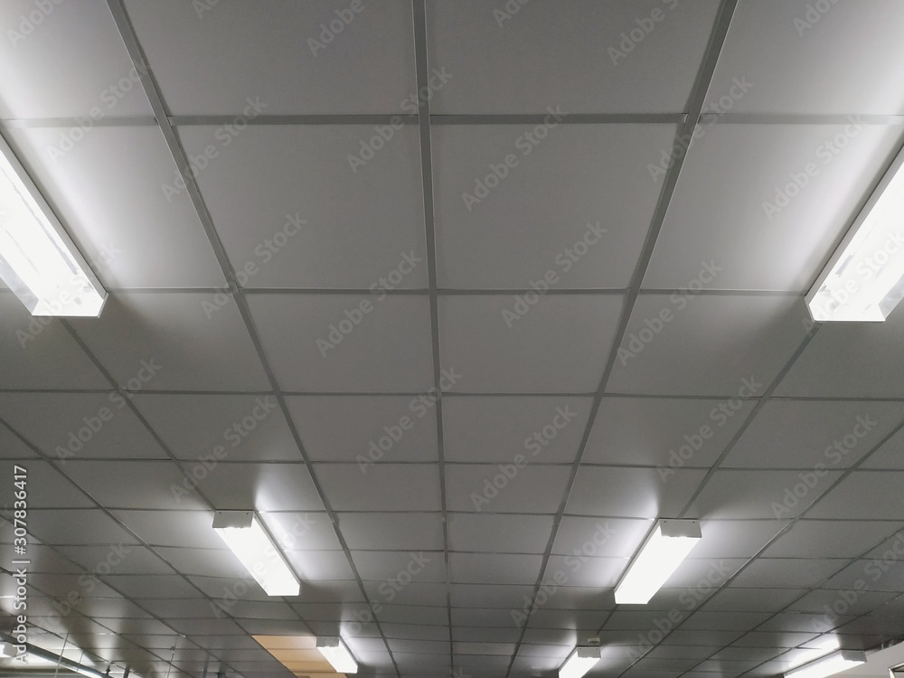The white ceiling in the building with light long-fluorescent lamps is illuminating.