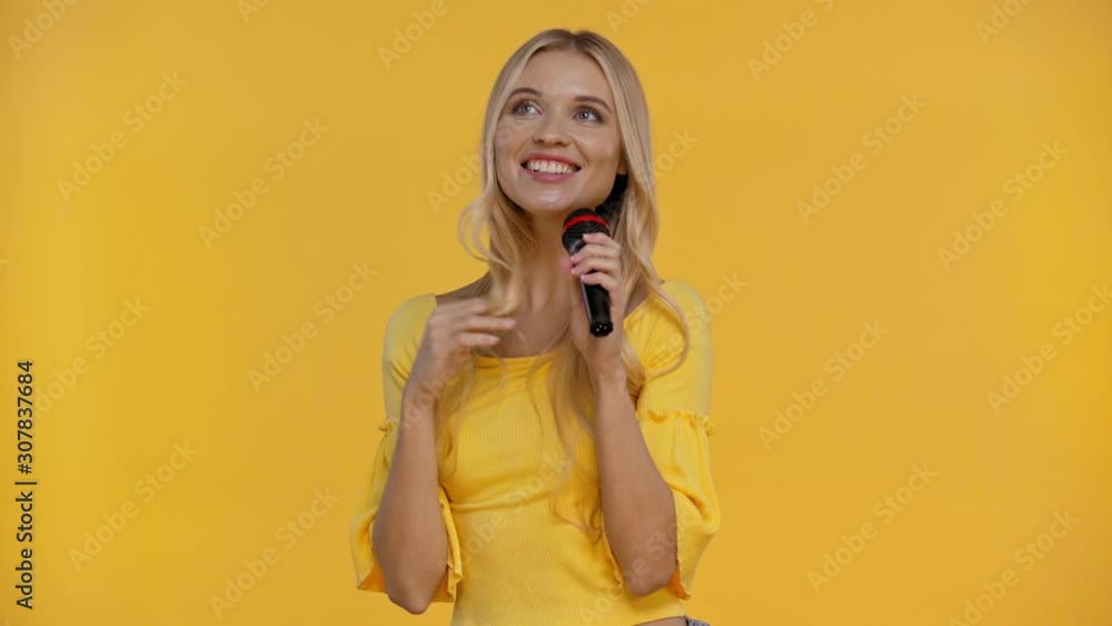 smiling woman speaking with microphone isolated in yellow smiling woman speaking with microphone isolated in yellow