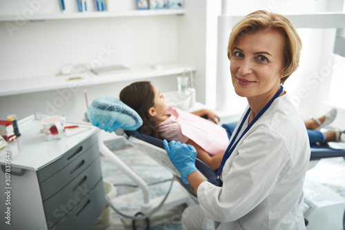 Waist up of a cheerful nice dentist sitting in her office