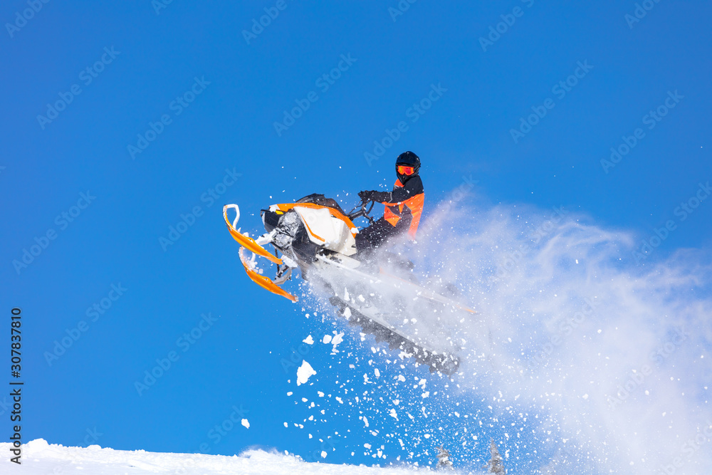 snowmobile jump straight up. the guy is flying and jumping on a snowmobile on a background of blue sky leaving a trail of splashes of white snow. bright snowmobile and suit. No brands. copy text snowmobile jump straight up. the guy is flying and jumping on a snowmobile on a background of blue sky leaving a trail of splashes of white snow. bright snowmobile and suit. No brands. copy text