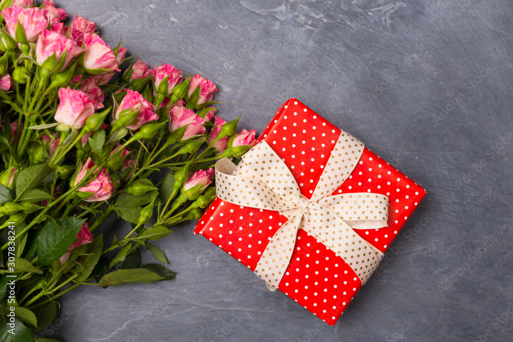 Obraz premium Close-up Pink spray roses gift in red box on grey background Woman's Day Mother's St. Valentine's Day concept Copy space