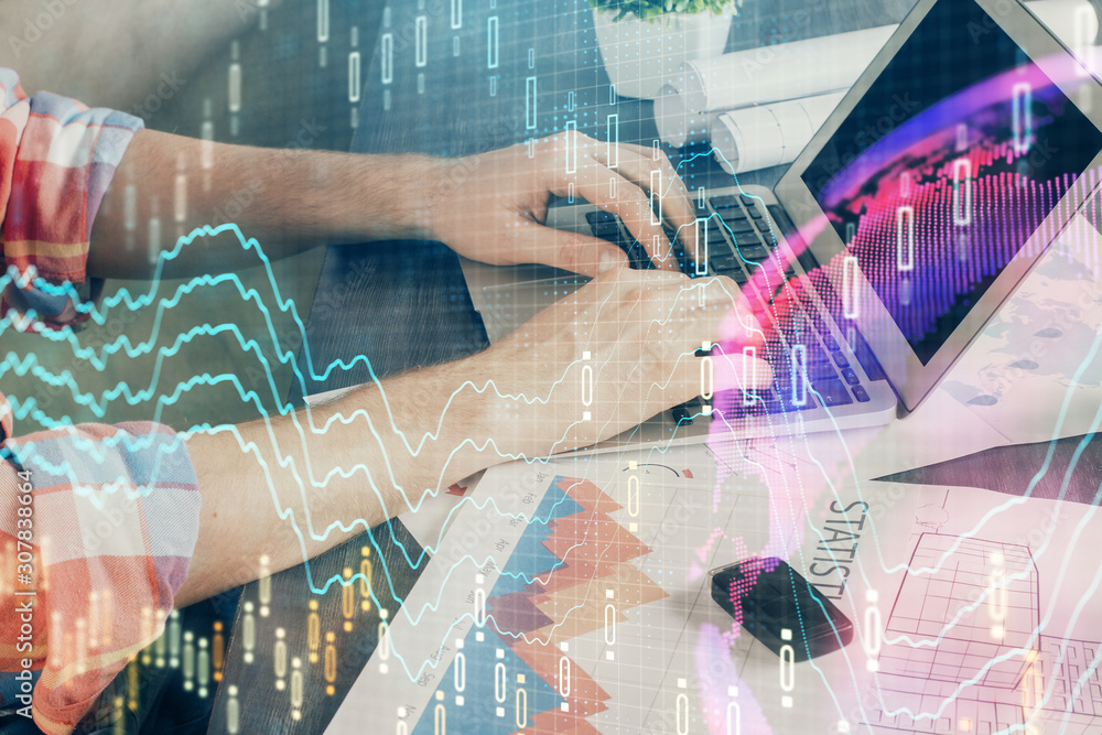 Double exposure of stock graph with businessman typing on computer in office on background. Concept of hard work.
