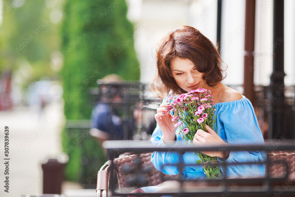 Outdoor portrait of beautiful woman at the table in a street city cafe ...