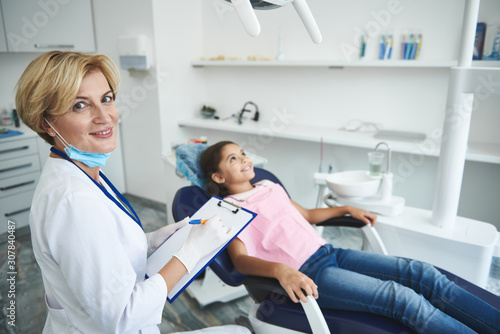 Smiling dentist is making diagnosis for young lady