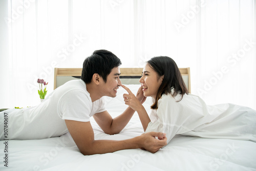 Cheerful Asian couple living together in bed room.