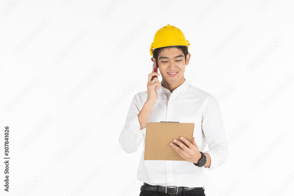 Asian handsome businessman wearing a yellow safety helmet looking and reading a document on a clipboard in his hand close up. Asian handsome businessman wearing a yellow safety helmet looking and reading a document on a clipboard in his hand close up.