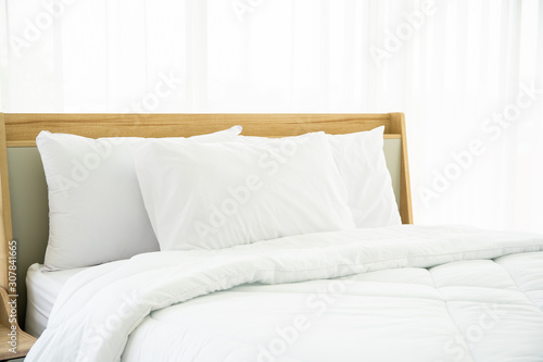 Bedroom decorated in minimal style, photograph of white pillows and wooden bed in bedroom with natural light from window. © DG PhotoStock