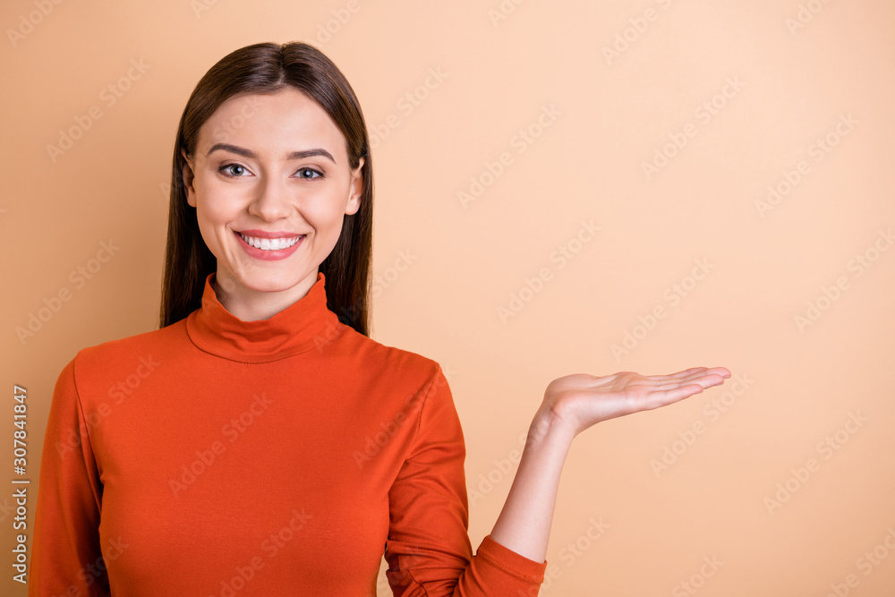 Photo of charming cheerful cute nice attractive manager holding something with her hand showing it to you isolated over beige pastel color background Photo of charming cheerful cute nice attractive manager holding something with her hand showing it to you isolated over beige pastel color background