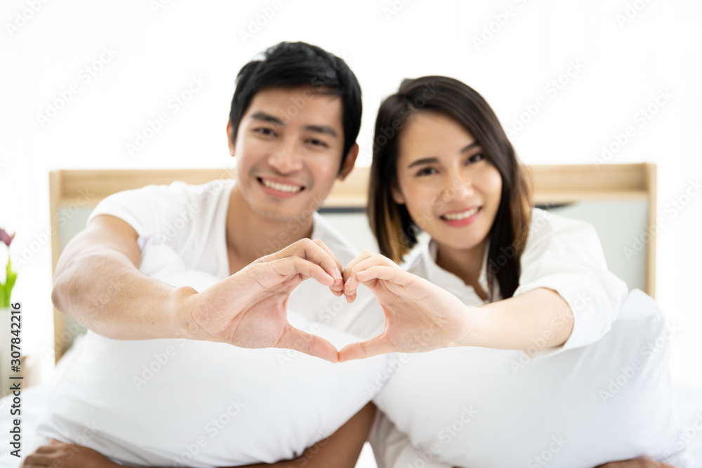 Funny and romantic Asian couple' portrait in bedroom with natural light from window, concept of relationship between husband and wife and being a family. Funny and romantic Asian couple' portrait in bedroom with natural light from window, concept of relationship between husband and wife and being a family.