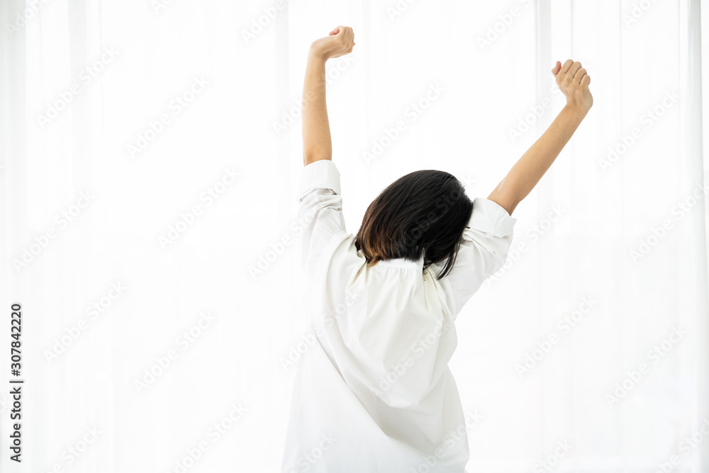 Pretty Asian woman in white shirt make stretching after woke up from the bed in morning, leisure and comfortable life concept. Pretty Asian woman in white shirt make stretching after woke up from the bed in morning, leisure and comfortable life concept.