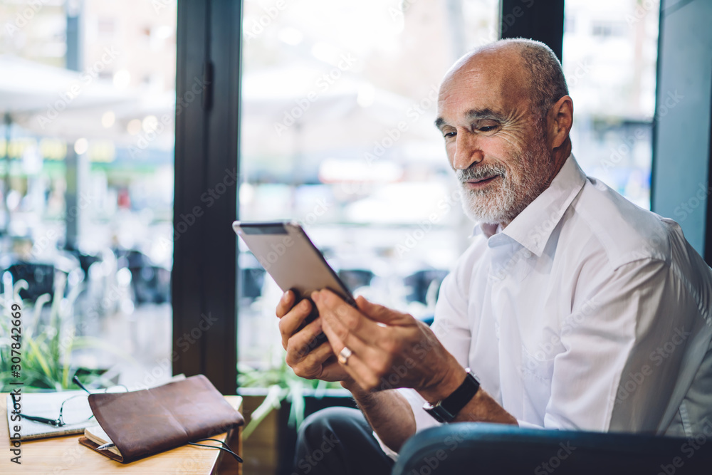 Senior cheerful male browsing tablet Senior cheerful male browsing tablet
