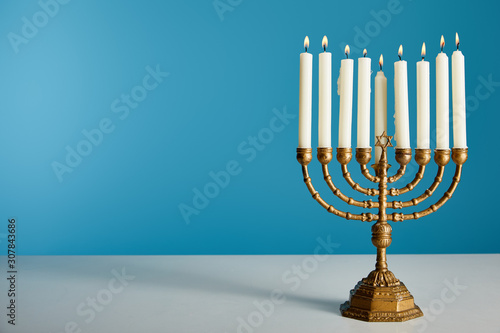 Burning candles in menorah isolated on blue photo