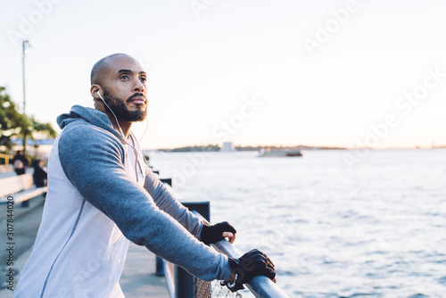 Fotografie Thoughtful adult black male in sportswear on seafront