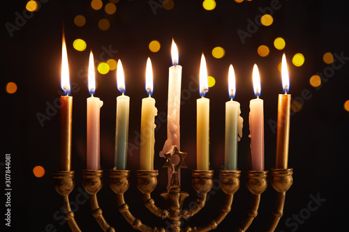 burning candles in menorah on black background with bokeh lights on Hanukkah