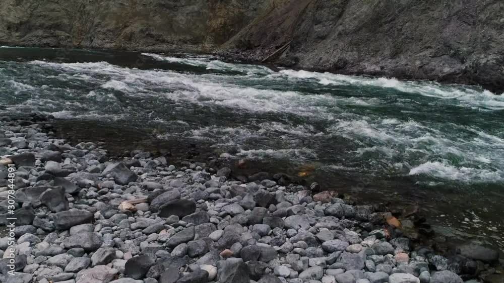 Drone, aerial, pushing forward, medium wide shot of a river flowing over rocky terrain. Drone, aerial, pushing forward, medium wide shot of a river flowing over rocky terrain.