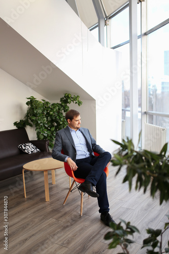Adult serious man businessman in a business suit working on a laptop, discussing business and ideas on the phone in his modern office.