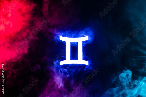 Blue illuminated Gemini zodiac sign with colorful smoke on background