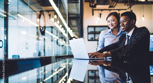 Diverse coworkers using laptop in modern office photo