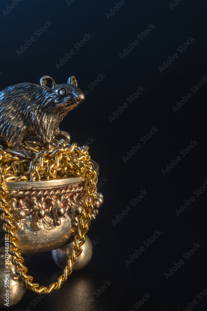 Composition from metal figures: a rat sits in a pot of gold. Products from silver and gold. Concept for the zodiac calendar in 2020. Symbol of well-being and prosperity and wealth. Black background Composition from metal figures: a rat sits in a pot of gold. Products from silver and gold. Concept for the zodiac calendar in 2020. Symbol of well-being and prosperity and wealth. Black background