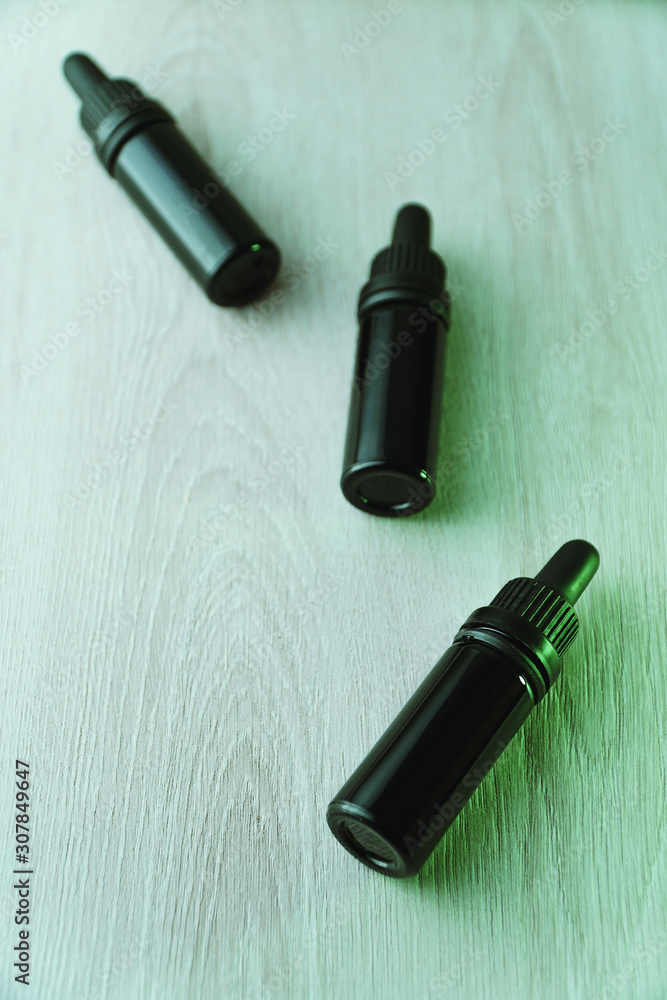 Three small black glass bottles on white wooden table Three small black glass bottles on white wooden table