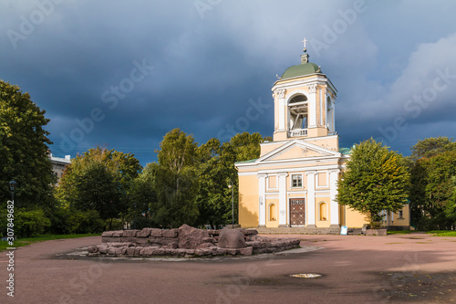 The Church of the Saints Peter and Paul illuminated by the sun on the background of trees and a thunderclouds, Vyborg, Leningrad Oblast, Russia