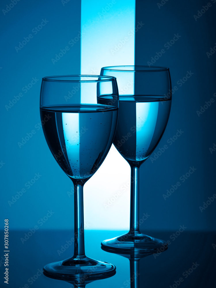 Two wine glasses silhouette full on blue background. Trendy color of the year 2020. Two wine glasses silhouette full on blue background. Trendy color of the year 2020.