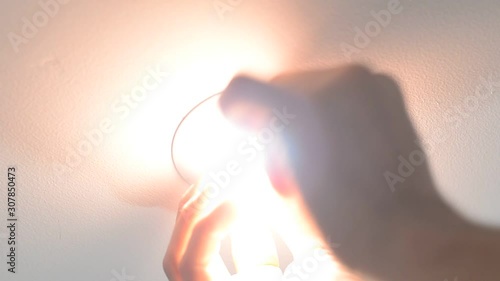 Electrician worker changes electric LED light bulb on the ceiling