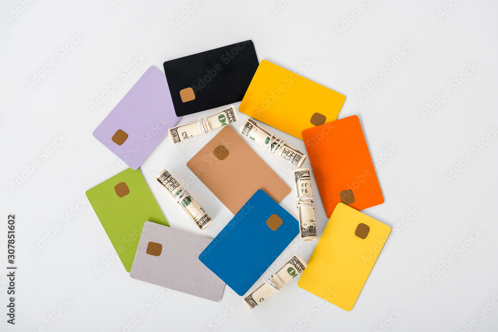 top view of multicolored credit card templates near cash rolls isolated on white top view of multicolored credit card templates near cash rolls isolated on white