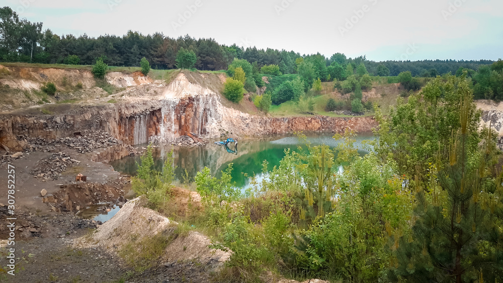 flooded quarry with water and an abandoned excavator