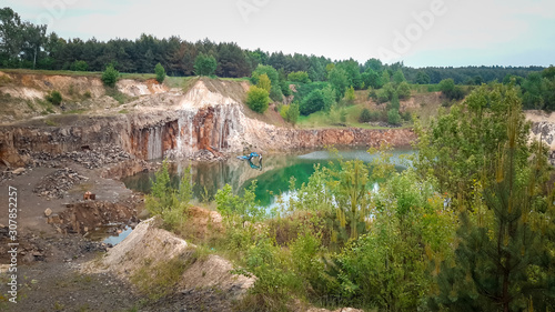 flooded quarry with water and an abandoned excavator